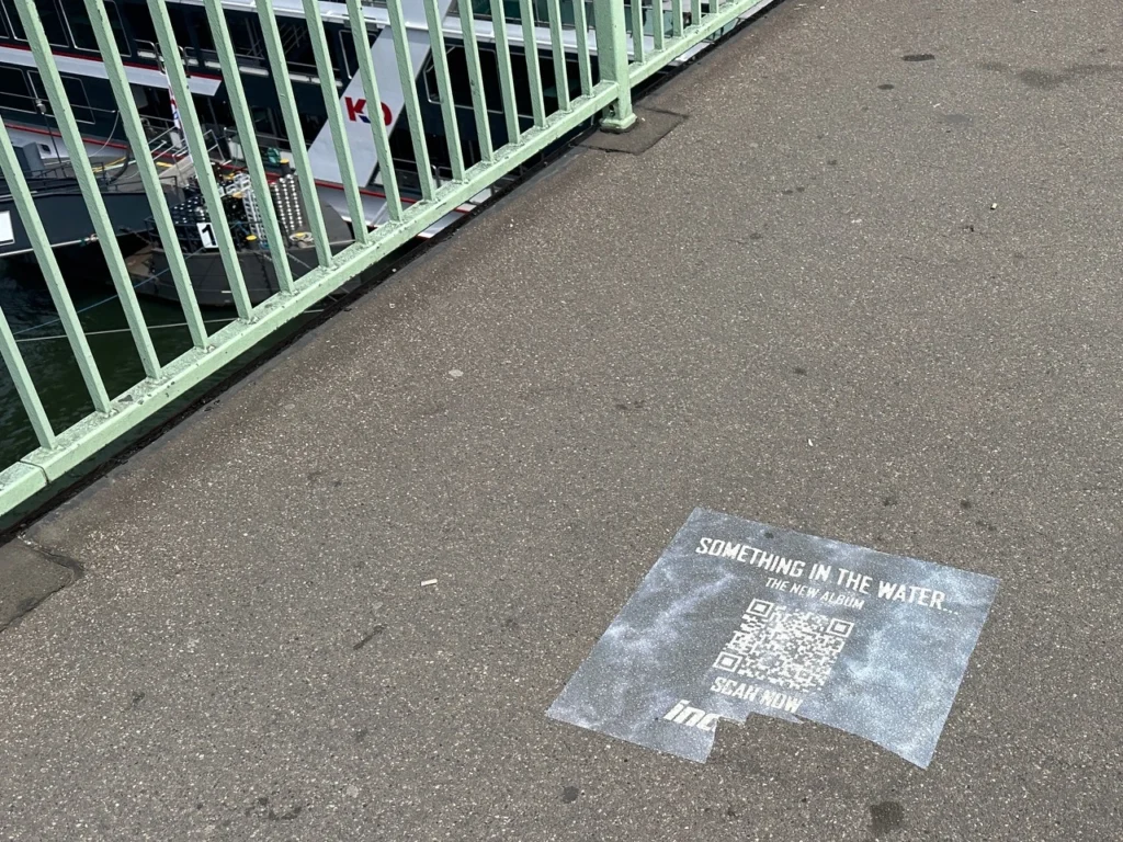 Gas Bild zeigt ein auf einen Gehweg geklebten Aufkleber auf einer Kölner Rheinbrücke als Beispiel für Guerilla-Marketing