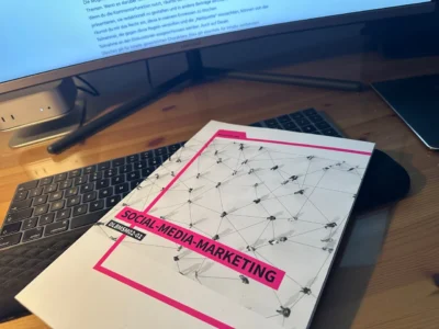 Es ist das Skript für Social-Media-Marketing der IU-Akademie zu sehen. Dieses liegt auf dem Schreibtisch von Martin.